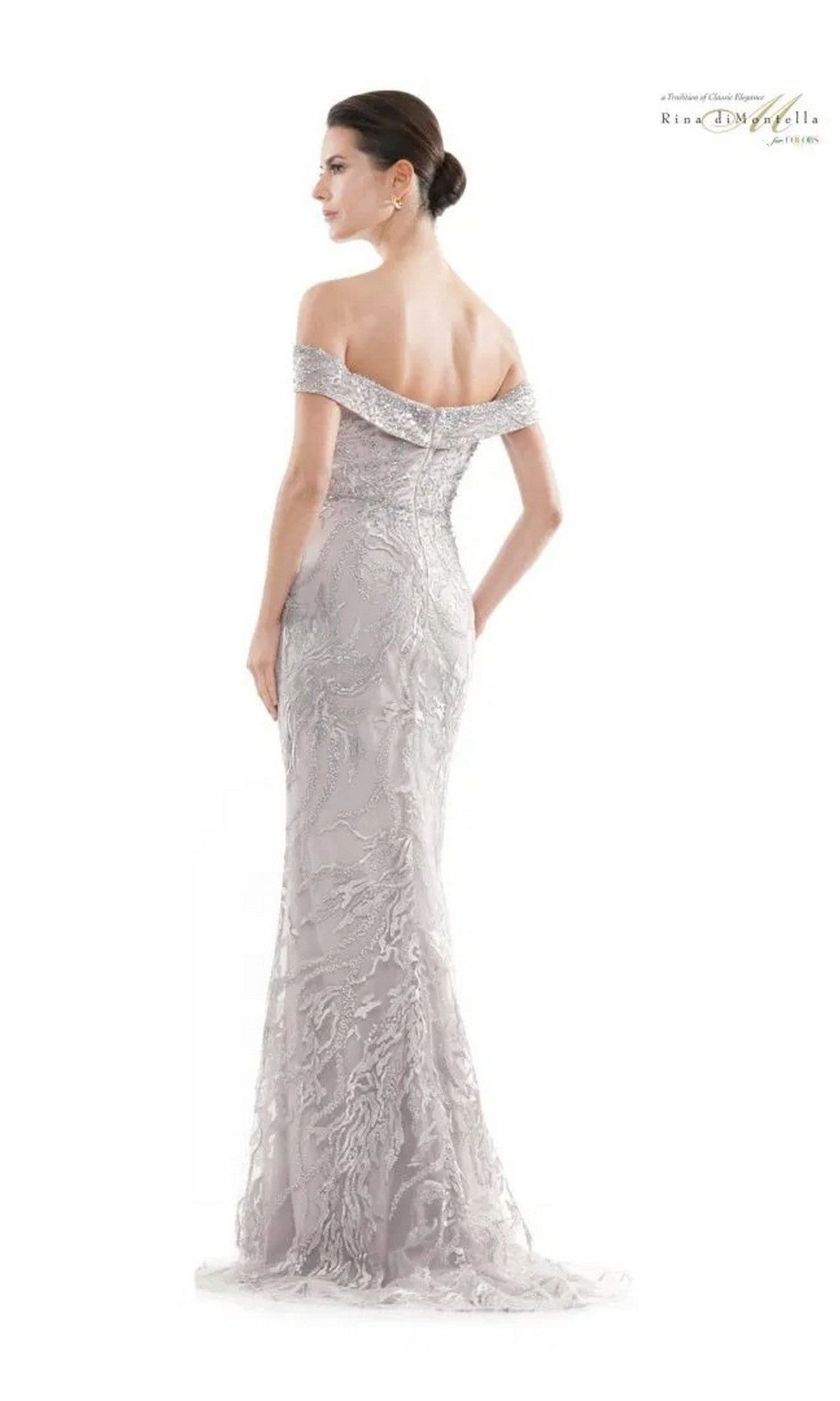 Woman in the Rina Di Montella RD2713 long formal dress with off-the-shoulder design and intricate lace embellishments stands with her back to the camera against a plain background.